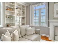Bright living room boasts custom built-ins, a fireplace, and large windows with waterfront views at 1 King St # 209 & 210, Charleston, SC 29401