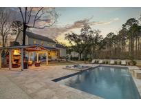 Stunning backyard featuring a pool, sun loungers, outdoor kitchen, and covered patio for ultimate relaxation at 1098 Reserve Ln, Awendaw, SC 29429