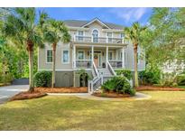 Inviting two-story home featuring double porches, complemented by lush landscaping and mature palm trees at 1143 Sea Eagle Watch, Charleston, SC 29412