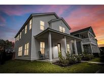 Charming two-story home with a covered front porch and inviting curb appeal at dusk at 165 Country Gate Ln, Summerville, SC 29485