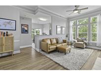 Bright living room featuring a leather sofa, ceiling fan, and large windows with natural light at 1735 Telfair Way, Charleston, SC 29412