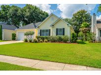 Charming one-story home with a well-manicured lawn and a two-car garage nestled amongst mature trees at 181 Sea Cotton Cir, Charleston, SC 29412