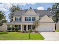 Inviting two-story home with a charming front porch, attached garage and lush landscaping at 7511 Hawks Cir, Hanahan, SC 29410