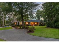 Charming brick home featuring a landscaped front yard, mature trees, and a welcoming entrance with a circular driveway at 110 W 2Nd South St, Summerville, SC 29483