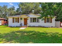Charming white brick home featuring manicured lawn, wood shutters, and inviting front porch at 111 Circle Dr, Summerville, SC 29485