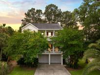 Charming two-story traditional home with a double porch and a two-car garage surrounded by lush greenery at 1417 S Jetties Ct, Mount Pleasant, SC 29466