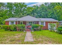 Charming red brick home with lush landscaping and inviting front porch at 1430 Brian Rd, Charleston, SC 29407