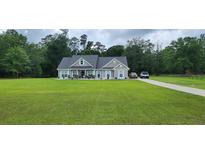 Charming single-story home with well-manicured lawn, inviting porch, and long driveway at 148 Hidden Hills Rd, Cross, SC 29436