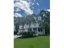 Charming two-story home with a well-manicured lawn, complemented by mature palm trees and a welcoming front porch at 1721 Wellstead St, Mount Pleasant, SC 29466