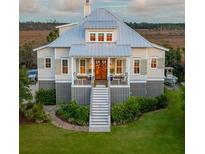 Charming elevated home with a metal roof, manicured lawn, and inviting front porch at 1809 Rushland Grove Ln, Johns Island, SC 29455