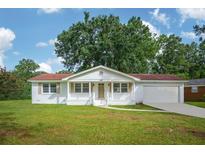 Charming white brick ranch-style home with a red roof, front porch, and attached garage nestled on a lush lawn at 2058 Bishop Dr, Charleston, SC 29414