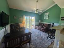 Relaxing living room featuring green walls, ceiling fan, and leather furniture on a vibrant patterned rug at 287 Driftwood Ln, Edisto Beach, SC 29438