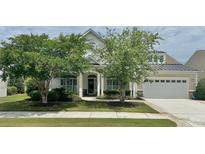 Charming home with a well-manicured lawn, mature trees, and inviting front porch at 310 Waterlily Way, Summerville, SC 29486