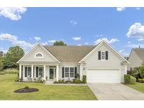 Charming home featuring a two-car garage, well-manicured lawn, and inviting front porch with comfortable seating at 349 Waterlily Way, Summerville, SC 29486