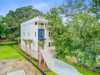 Stunning exterior view of a modern, multi-story home with a stairway, lush landscaping and a blue accent panel at 501 Joseph St, Charleston, SC 29412