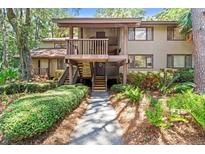 Inviting two-story condo with a charming wooden walkway surrounded by lush greenery and a pathway leading to the entrance at 1326 Sea Elder Dr, Kiawah Island, SC 29455