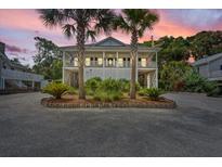 Charming two-story beach house with double palm trees, covered porch, and a spacious driveway at 1604 Jungle Rd, Edisto Island, SC 29438