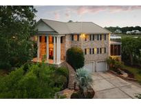 Stately brick home boasts an elegant facade with columns, a metal roof, and lush landscaping at 2834 Parkers Landing Rd, Mount Pleasant, SC 29466