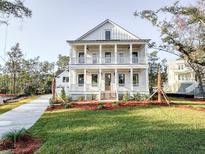 Stunning two-story white home with inviting double porches and beautifully landscaped front yard at 3898 Summerton Street Dr, Mount Pleasant, SC 29466