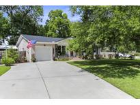 Charming home with a well-manicured lawn, inviting driveway, attached garage and beautiful flowering trees at 414 Birch Ave, Goose Creek, SC 29445