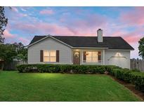Charming single-story home with well-manicured lawn and inviting front porch with hanging flower baskets at 8692 Bentwood Dr, North Charleston, SC 29406