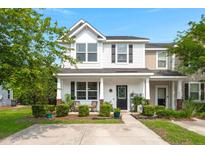 Charming two-story home with a well-manicured lawn, covered porch, and classic architectural details at 9049 Parlor Dr, Ladson, SC 29456