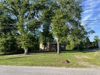 Charming single-story brick home nestled among mature trees with a lush green lawn at 9612 Hoot Owl Ave, Ladson, SC 29456