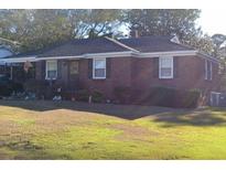 Cozy brick home featuring a well-maintained lawn, trimmed shrubs, and a welcoming front entrance at 1237 Fort Dr, Hanahan, SC 29410
