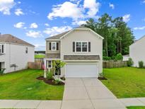 Charming two-story home featuring neutral siding, an attached garage, and a well-manicured lawn at 141 Sweet Cherry Ln, Summerville, SC 29486