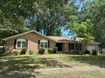 Charming brick home with a lush, tree-filled front yard creating a serene and inviting curb appeal at 2827 Haverhill Cir, North Charleston, SC 29420