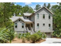 Charming two-story home with a landscaped yard and staircase leading to the front door at 3125 Privateer Creek Rd, Seabrook Island, SC 29455