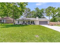 Charming single-story home with a well-manicured lawn and inviting curb appeal on a sunny day at 402 Woodward Blvd, Summerville, SC 29483