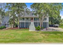 Charming raised home featuring lush landscaping, a large yard, and a welcoming front porch at 634 Lynne Ave, Charleston, SC 29412