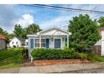 Charming cottage-style home featuring blue shutters, a landscaped yard, and a cozy front porch at 9 F St, Charleston, SC 29403
