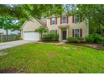 Charming two-story home with beige siding, red shutters, a well-manicured lawn, and an attached two-car garage at 1629 Jorrington Street St, Mount Pleasant, SC 29466