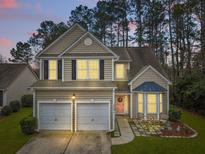 Charming two-story home with a manicured lawn, two-car garage, and welcoming pink front door at 2004 Hammond Dr, Mount Pleasant, SC 29466