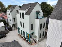 An exterior view of a three-story home with a gravel driveway and bright turquoise accents at 3 1/2 Maranda Holmes St # B, Charleston, SC 29403