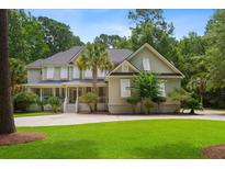 Charming two-story home with a well-manicured lawn, covered front porch, and mature trees in a serene, landscaped setting at 3171 Pignatelli Cres, Mount Pleasant, SC 29466