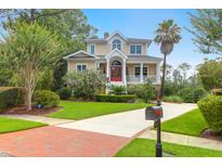 Beautiful two-story home featuring a red door, a columned porch and a brick-paved driveway at 391 Evian Way, Mount Pleasant, SC 29464