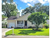 Charming single-story home featuring a well-manicured lawn and a lovely front porch and attached garage at 4457 Rice Mill Dr, North Charleston, SC 29420