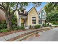 Charming two-story home with yellow siding, black door, inviting porch, and lush landscaped yard at 5134 E Liberty Park Cir, North Charleston, SC 29405