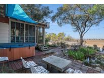Inviting backyard with a hot tub, a screened porch and a fire pit with pond and seating area at 520 E Huron Ave, Folly Beach, SC 29439