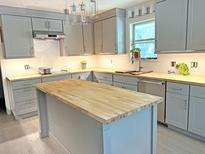 Modern kitchen featuring gray cabinets, butcher block countertops, an island, and stainless steel appliances at 1014 E Cooper Ave, Folly Beach, SC 29439