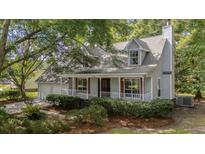 Charming home with a cozy front porch, red shutters, white rails, and beautifully landscaped yard at 202 Woodbridge Dr, Summerville, SC 29486
