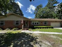 Charming brick home featuring an attached garage, green shutters, and manicured lawn at 409 Azalea Dr, Walterboro, SC 29488