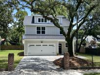 Charming two-story home featuring a two-car garage, white exterior, and a beautiful mature tree in the front yard at 641 Magnolia Rd, Charleston, SC 29407