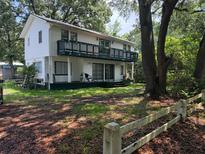 Two-story home with a spacious balcony and a large yard enclosed by a rustic wooden fence at 102 Webb St, Bonneau, SC 29431
