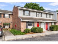 A cozy townhouse with brick and siding, black shutters, and a vibrant red door, enhancing curb appeal at 2362 Parsonage Rd # 2H, Charleston, SC 29414