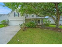 Charming two-story home with a well-manicured lawn and mature shade trees. Covered porch and attached garage at 468 Maple Oak Ln, Charleston, SC 29414