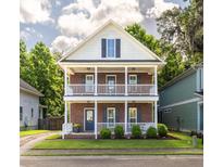 Charming two-story home features a brick facade and double balconies with lush landscaping at 5110 Hyde Park Village Ln, North Charleston, SC 29405